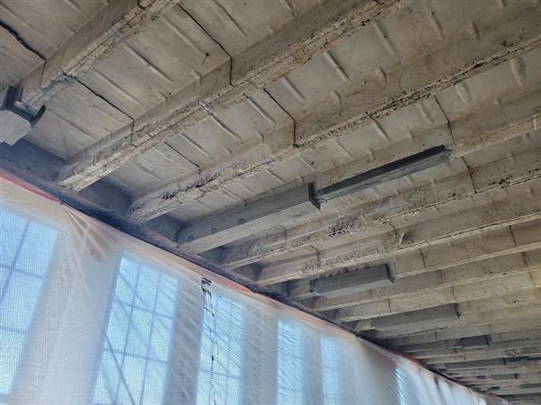 Existing concrete beam ceiling being patched on fourth floor 